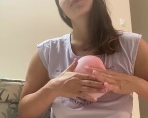 Woman plays with small pink balloon (the balloon doesn't burst)